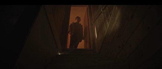 Man standing in open doorway at top of stairs
