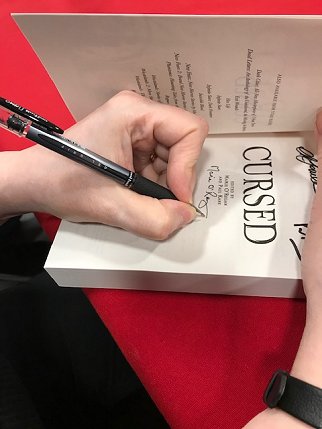 Marie O'Regan signing a copy of Cursed, edited by Marie O'Regan and Paul Kane
