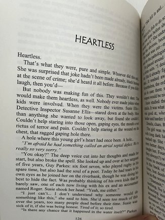 Picture of a book being held open to the title page of a story, 'Heartless'