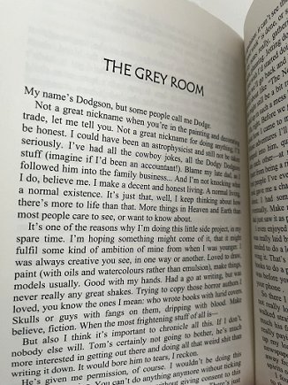 Picture of a book being held open to the title page of a story, 'The Grey Room'