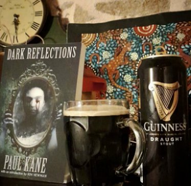 photograph showing a standing copy of the book Dark Reflections by Paul Kane, beside a full tankard of Guiness and a Guinness draught can