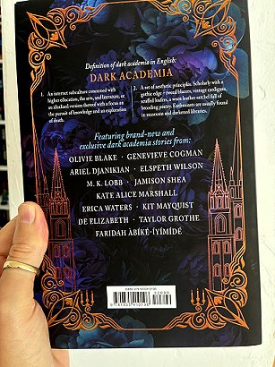 photograph of a man's hand holding up a copy of These Dreaming Spires, edited by Marie O'Regan and Paul Kane, to show the back cover