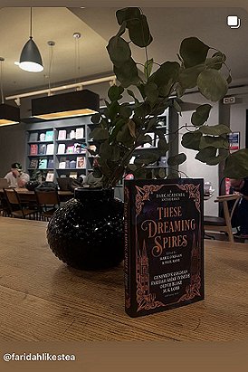 photograph of a copy of These Dreaming Spires, edited by Marie O'Regan and Paul Kane, standing on a wooden surface in front of a dark circular vase with several rose stems inside