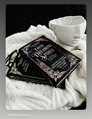 photograph showing copies of These Dreaming Spires, edited by Marie O'Regan and Paul Kane, lying on a white cloth beside a white vase of the lower half of a face. To the left is a black-rimmed pair of glasses