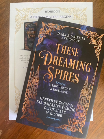 photograph of a copy of These Dreaming Spires, edited by Marie O'Regan and Paul Kane, on a wooden surface, with a copy of the press release for the book underneath