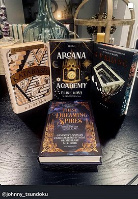 photograph showing a copy of These Dreaming Spires, edited by Marie O'Regan and Paul Kane, lying on a dark wooden surface. Standing behind These Dreaming Spires are three other hardback books