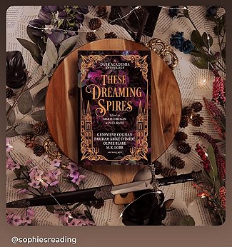 photograph showing a copy of These Dreaming Spires, edited by Marie O'Regan and Paul Kane, lying on a circular wooden surface on top of loose book pages scattered with purple flowers and leaves. At the bottom of the picture is a dagger