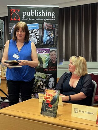 Photograph of Marie O'Regan in a blue top and black trousers, and Tracy Fahey in a black dress, as Marie introduces 2023's Absinthe novellas