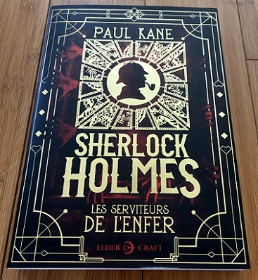 photograph showing a copy of the French edition of Sherlock Holmes and the Servants of Hell by Paul Kane, on a wooden surface