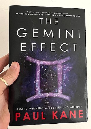 image of a man's hand holding up a copy of a book, The Gemini Effect, by Paul Kane