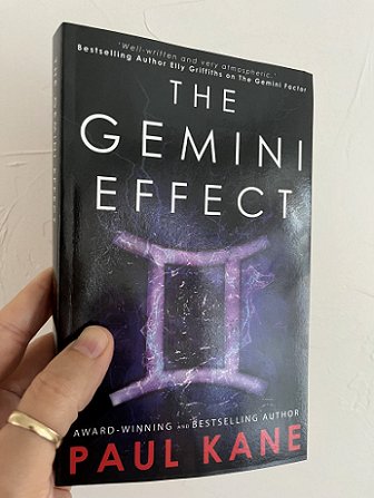 image of a man's hand holding up a copy of a book, The Gemini Effect by Paul Kane