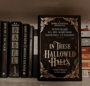 photograph showing a copy of In These Hallowed Halls, edited by Marie O'Regan and Paul Kane, standing in front of a row of other books, including Babel by R F Kuang.