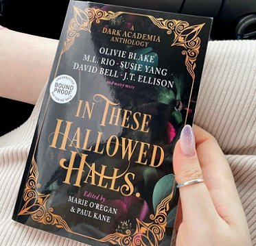 Image of a woman's hand holding a copy of In These Hallowed Halls, edited by Marie O'Regan and Paul Kane