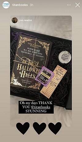 screenshot of a black box on a white surface, the box contains a copy of In These Hallowed Halls, edited by Marie O'Regan and Paul Kane, tied up with string, a bookmark, a teabag and a candle