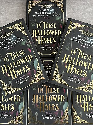 A display of six copies of In These Hallowed Halls, edited by Marie O'Regan and Paul Kane, lying on a grey background