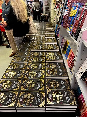 A side view of a table containing a few hundred copies of In These Hallowed Halls, edited by Marie O'Regan and Paul Kane, at Forbidden Planet London Megastore