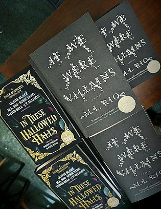 a display of signed copies of If We Were Villains by M L Rio and In These Hallowed Halls, edited by Marie O'Regan and Paul Kane, on a wooden table