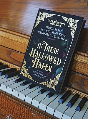 photograph showing a copy of In These Hallowed Halls, edited by Marie O'Regan and Paul Kane, standing on top of piano keys and leaning against the wooden piano frame