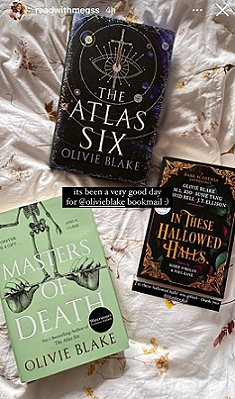 Copies of Masters of Death and The Atlas Six by Olivie Blake, and In These Hallowed Halls, edited by Marie O'Regan and Paul Kane, lying on a cream cloth decorated with yellow flowers