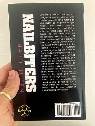 Man's hand holding a copy of Nailbiters: Hard Bitten by Paul Kane, showing the back cover text