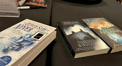 Display of three books on a black cloth. The Other Side of Never, edited by Marie O'Regan and Paul Kane, Darkness and Shadows by Paul Kane, and Arcana by Paul Kane