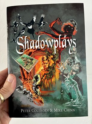 photograph showing a hand holding up a copy of Shadowplays, edited by Peter Coleborn and Mike Chinn