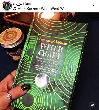 screenshot from @av_wilkes. Image shows a woman's hand holding up a copy of Beyond and Within Witchcraft, edited by Marie O'Regan and Paul Kane