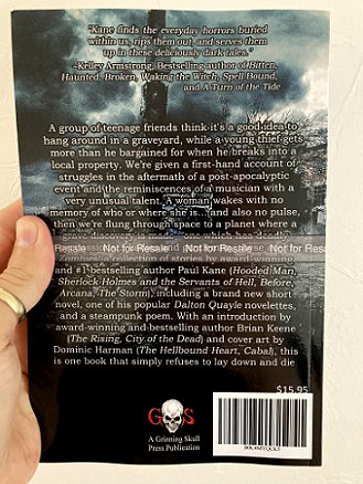 A man's hand holding Zombies! by Paul Kane, showing the back cover text