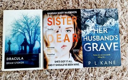 Books arranged on carpet, including Her Husband's Grave by P L Kane