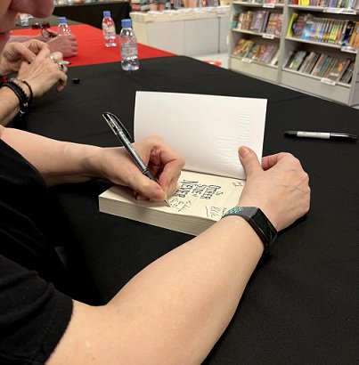 Marie O'Regan signing a copy of The Other Side of Never, edited by Marie O'Regan and Paul Kane