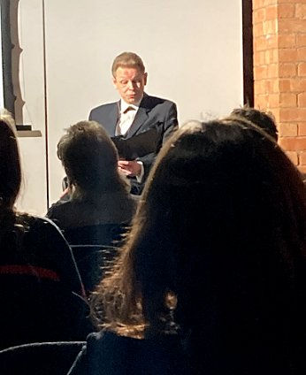 Image of man on stage reading